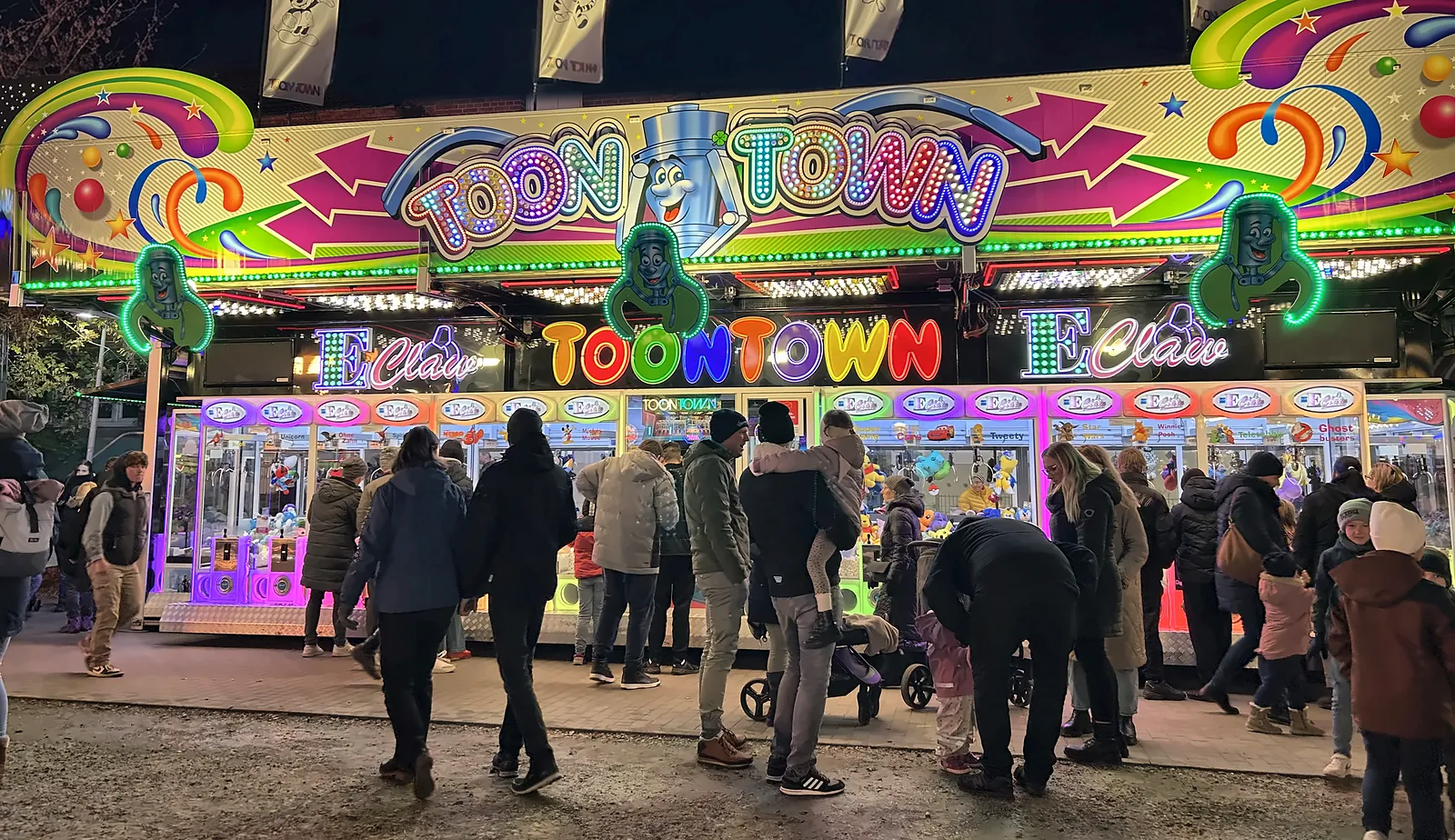 Toon Town am Abend: die zwölf Meter lange, bunt leuchtende Automatenfront, davor dicht an dicht Besucher mit Kindern.