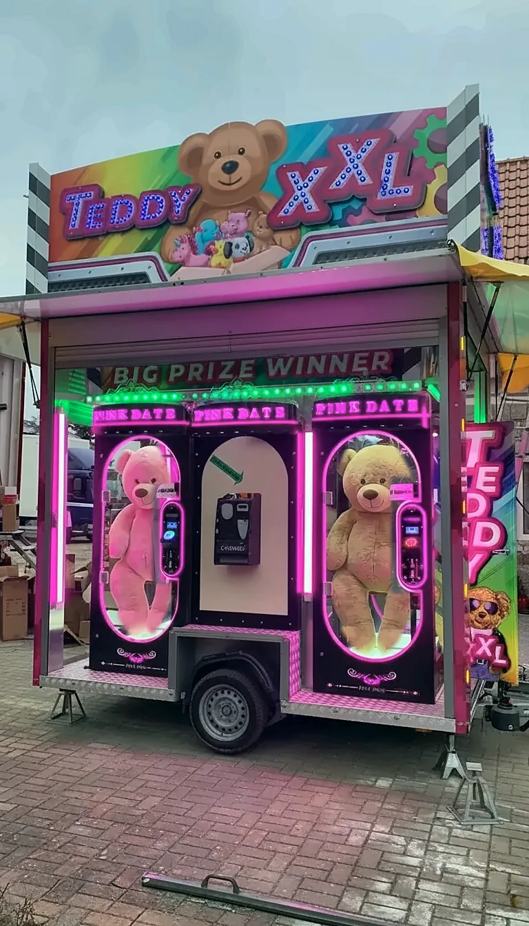 Teddy XXL: pinker Anhänger mit beleuchteten Greifautomaten und großem Teddy-Schild.