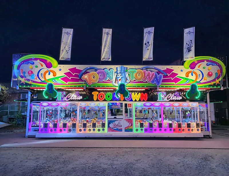 Toon Town frontal bei Nacht: durchgehende Reihe beleuchteter Greifautomaten, in der Mitte die Kasse, darüber der große Leuchtschriftzug.